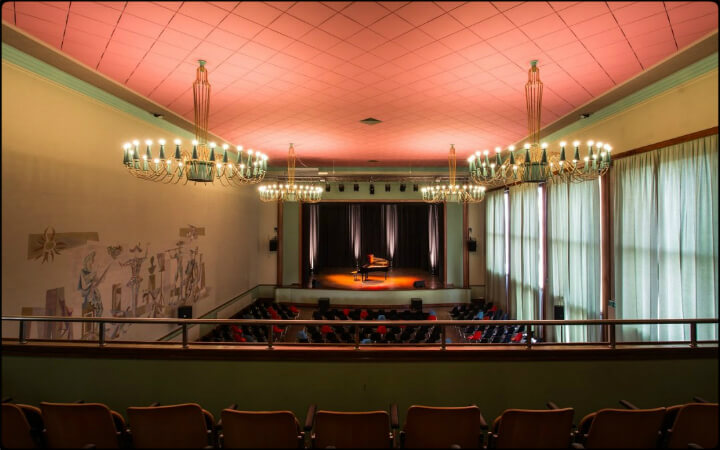 Salle de spectacle de Renens vue du balcon, plafond saumon et lustres en cristal au-dessus des fauteuils