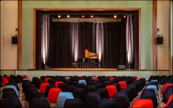 Scène de la salle de spectacle de Renens avec son piano à queue, vue depuis les fauteuils