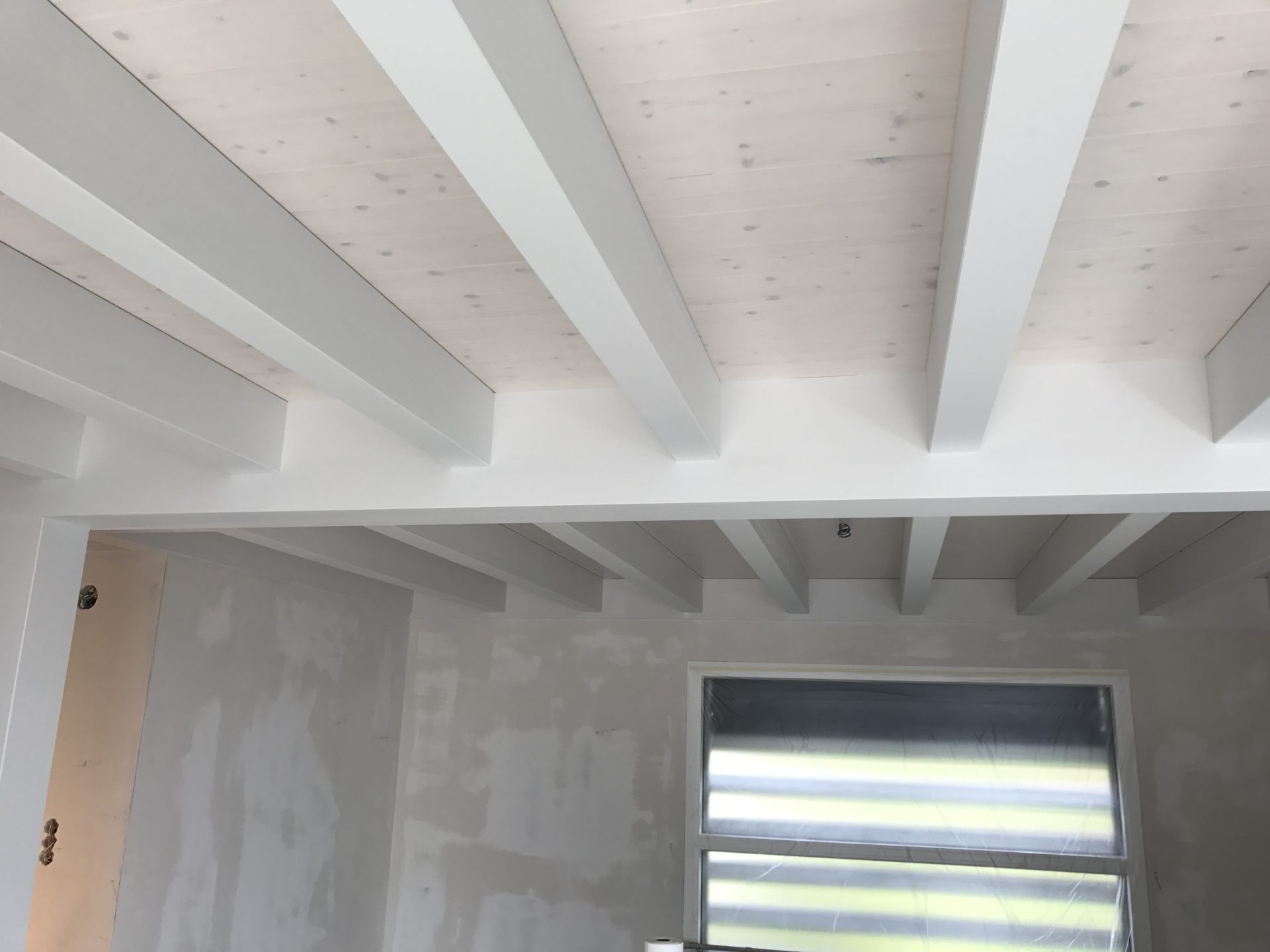 Plafond en lambris et poutres peint en blanc dans l'ancienne ferme rénovée