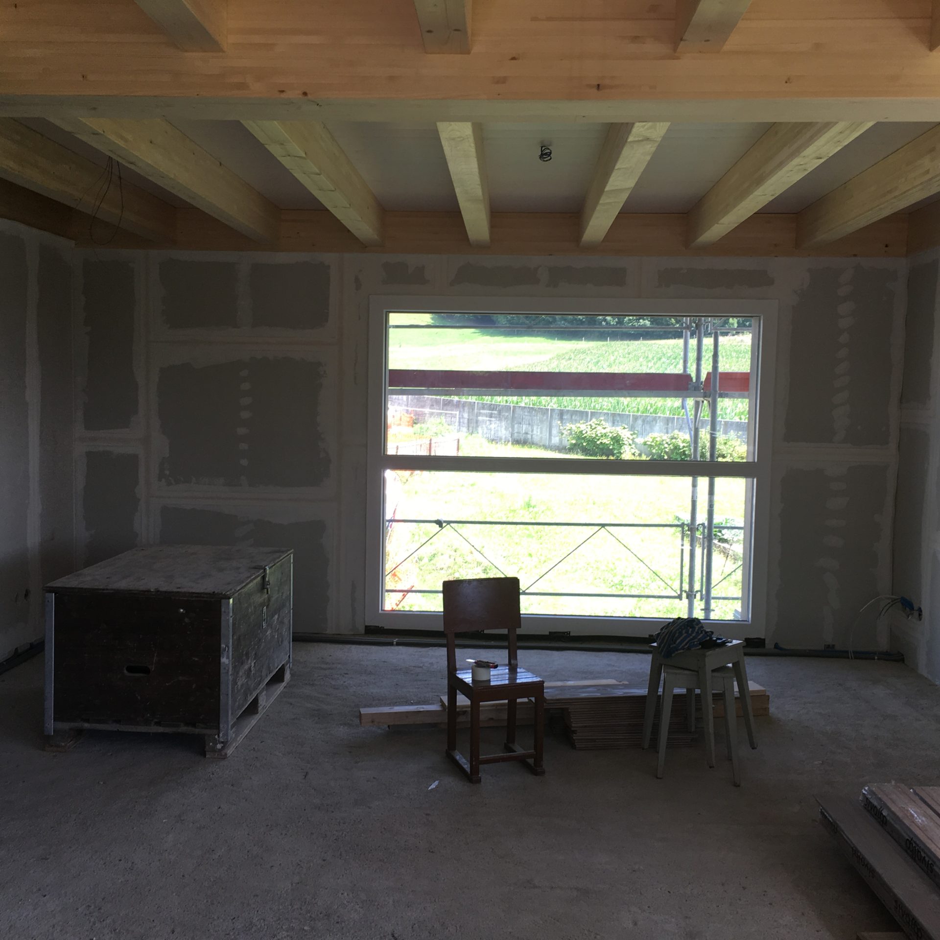 Pièce en chantier de l'ancienne ferme, plafond à poutres claires et cloisons de plâtre jointoyées