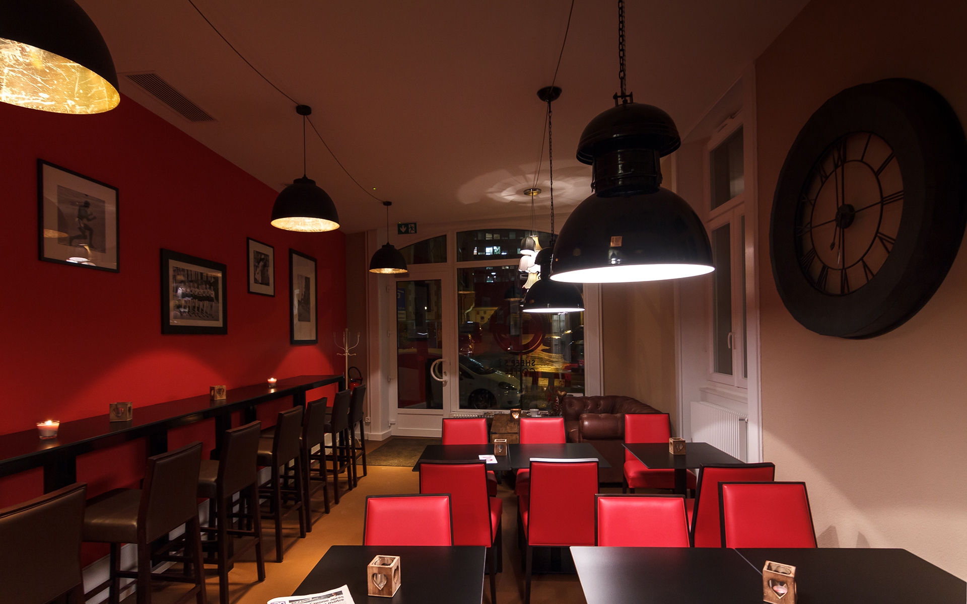 Comptoir haut et suspensions industrielles du Sheep's Coffee, chaises rouges et grande horloge murale