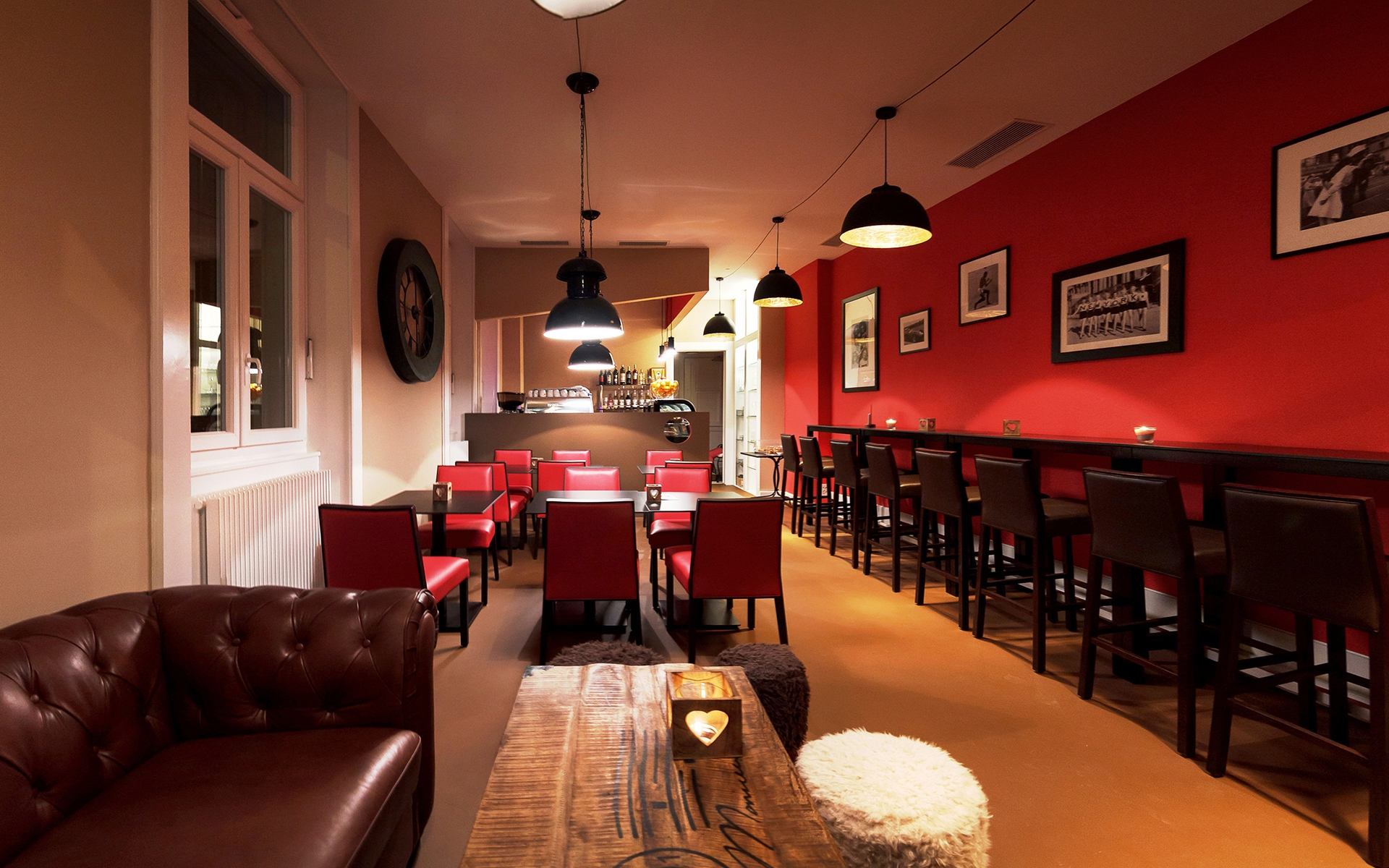 Salle du café Sheep's Coffee à Lausanne, murs rouges, banquette en cuir et cadres au mur
