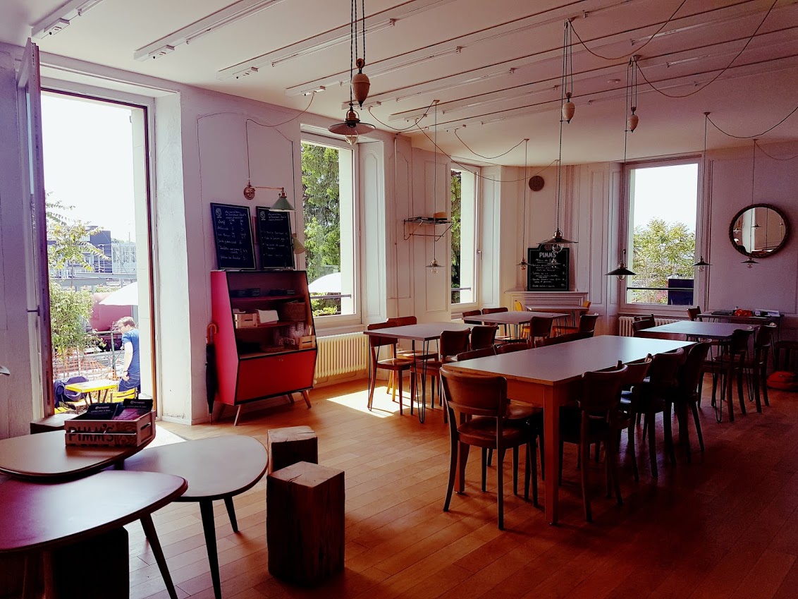 Salle du café de la Ferme des Tilleuls, murs roses et longues tables en bois