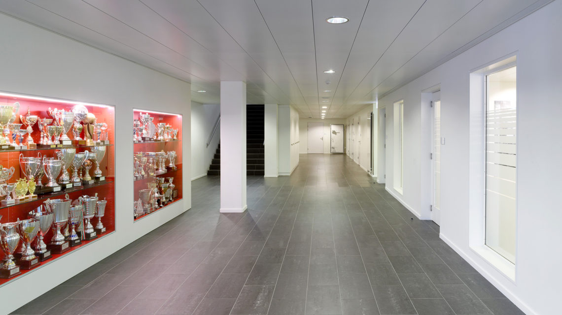 Couloir de l'International School of Lausanne bordé d'une vitrine de trophées éclairée