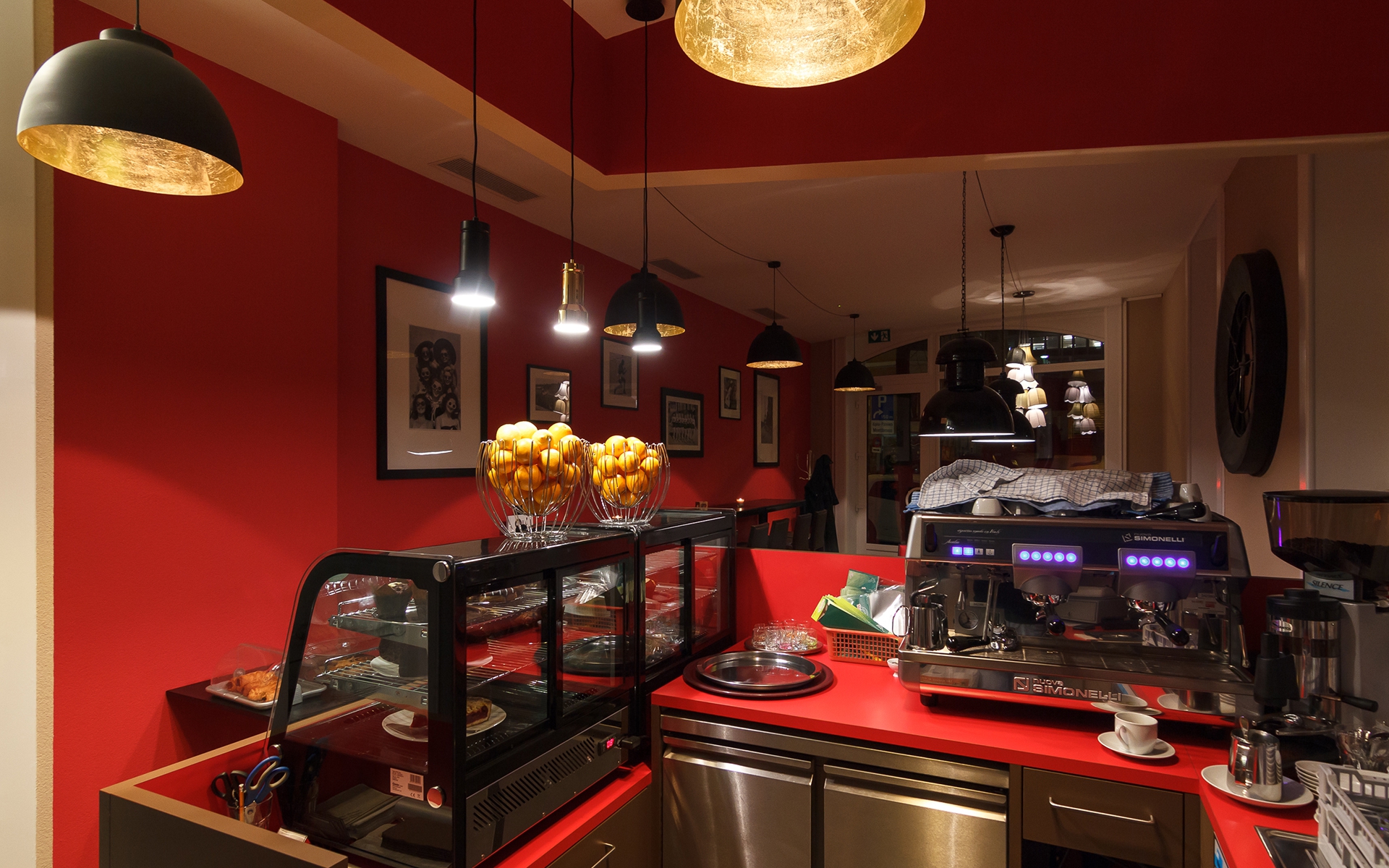 Bar du Sheep's Coffee avec sa vitrine à pâtisseries et sa machine à café devant le mur rouge