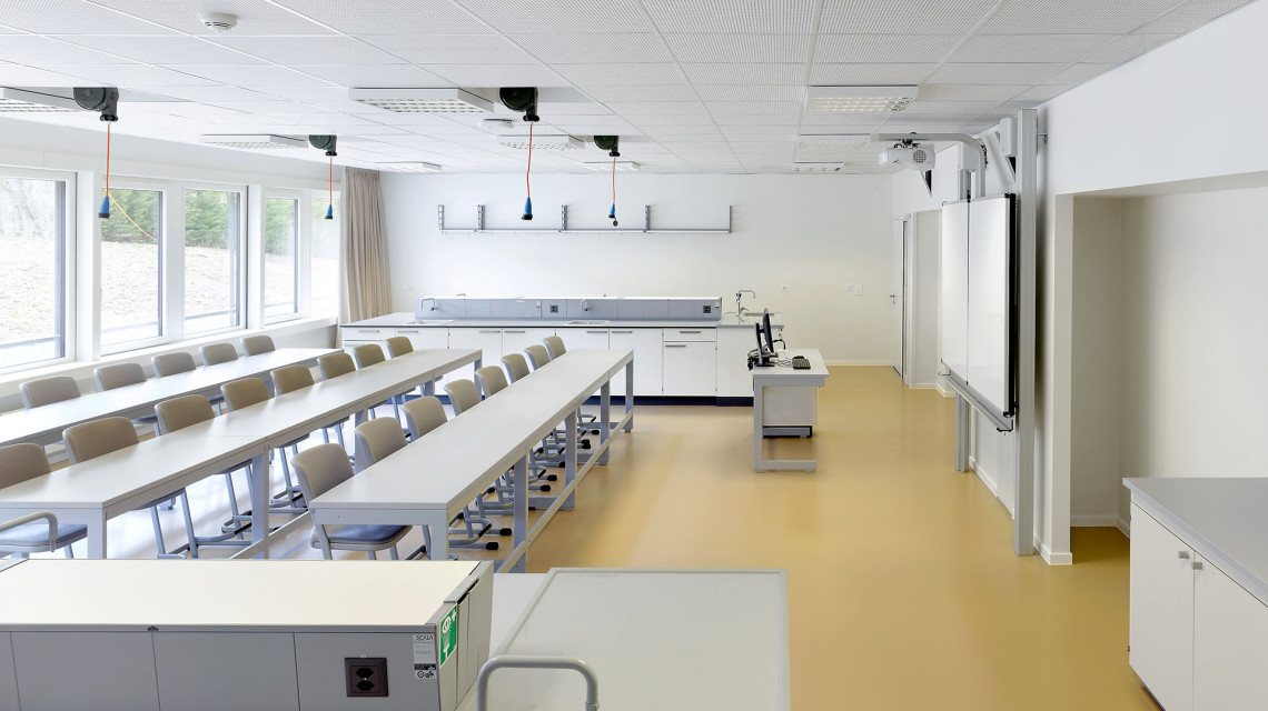Salle de classe de l'International School of Lausanne avec ses longues tables blanches et son sol beige