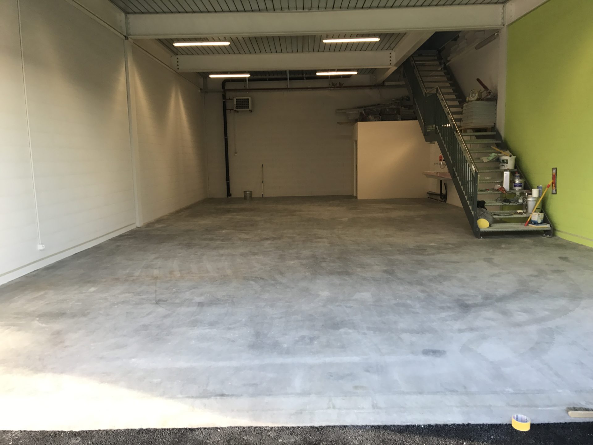 Halle de l'atelier G. Pucci SA en travaux, mur vert anis et escalier métallique