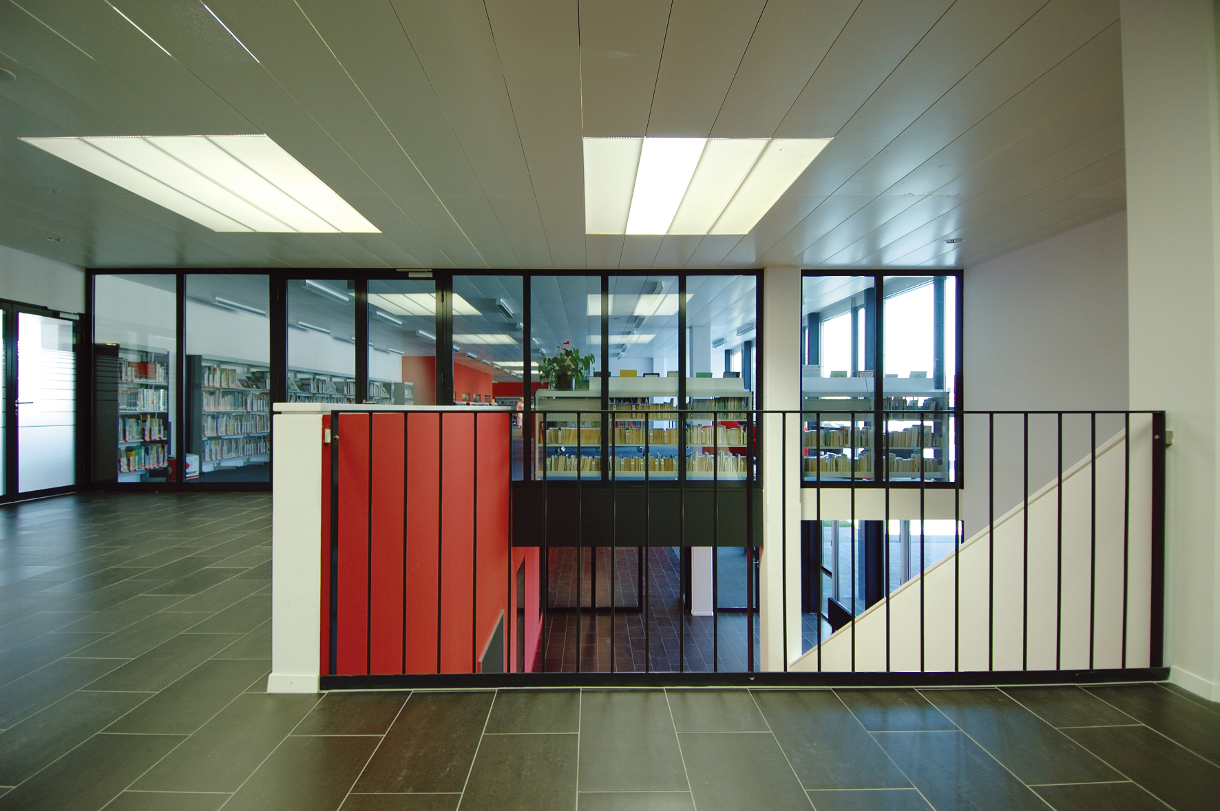 Mezzanine de la bibliothèque de l'International School of Lausanne, garde-corps métallique et cage d'escalier rouge