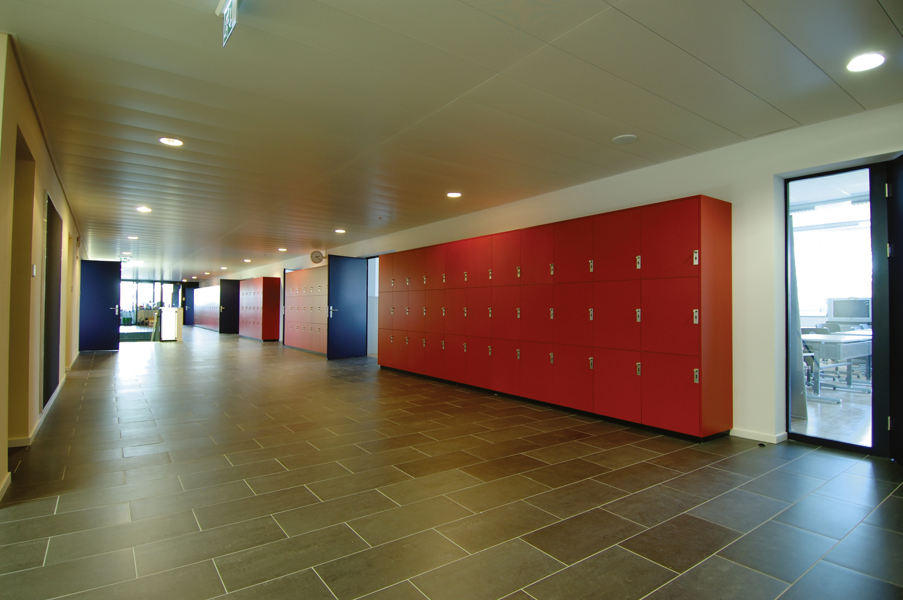 Couloir de l'International School of Lausanne bordé d'une longue rangée de casiers rouges