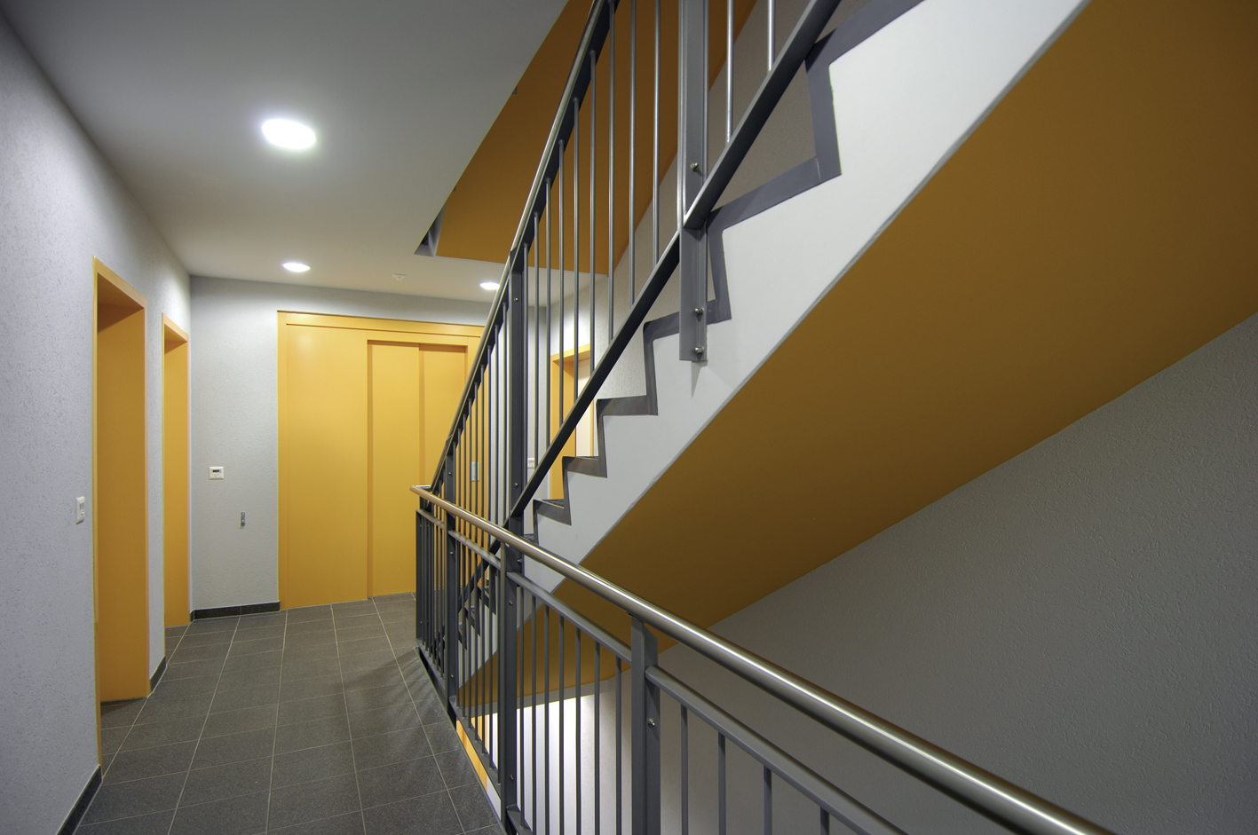 Palier des Balcons de Vallombreuse, mur jaune et garde-corps métallique de la cage d'escalier