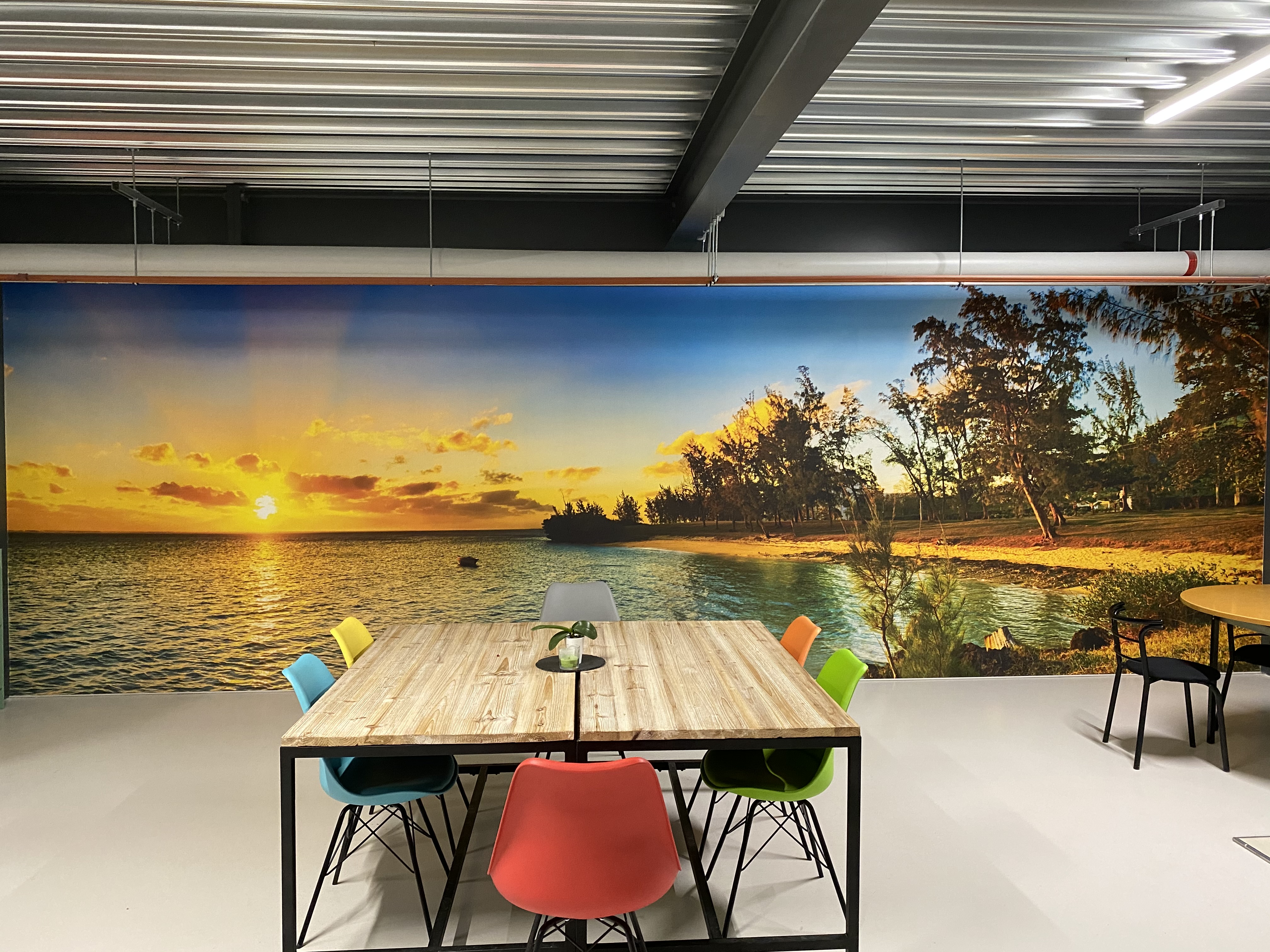 Salle de pause de l'atelier G. Pucci SA, mur imprimé d'un panorama de plage et grande table de réunion
