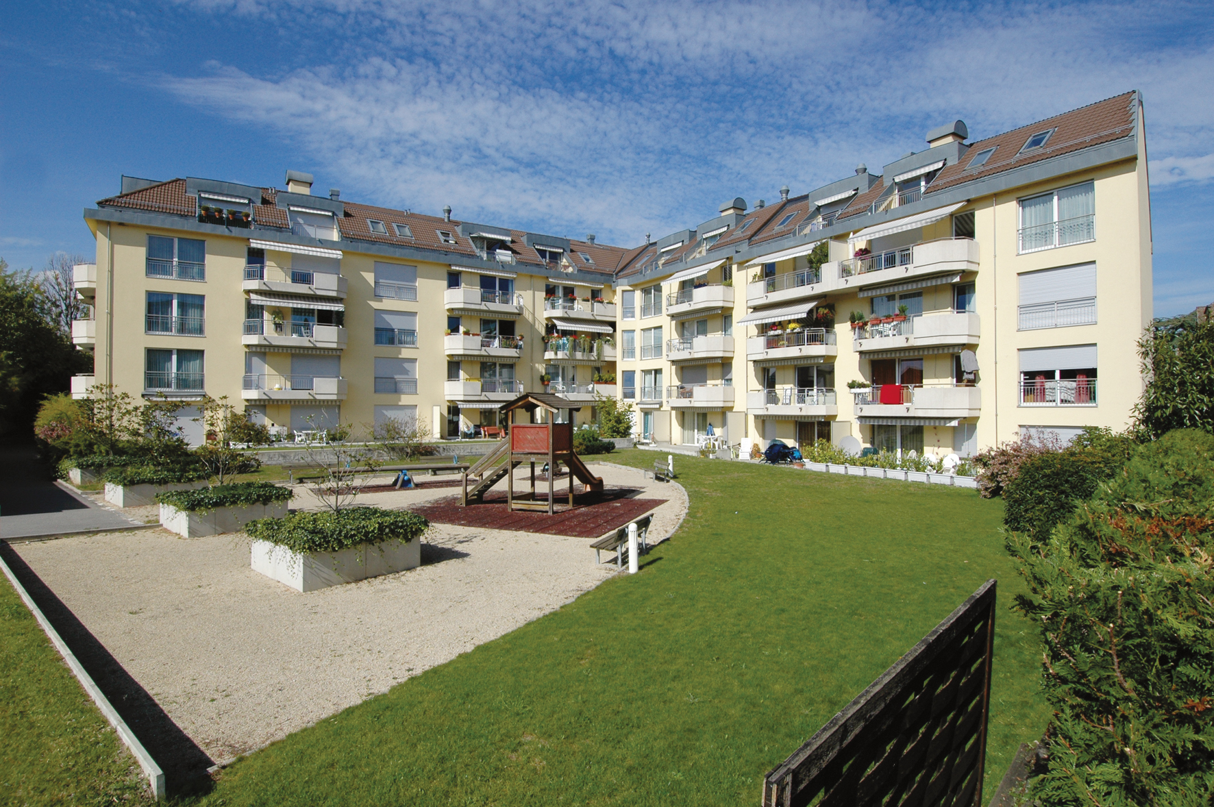 Cour intérieure de la résidence Sablons A avec sa place de jeux et sa pelouse
