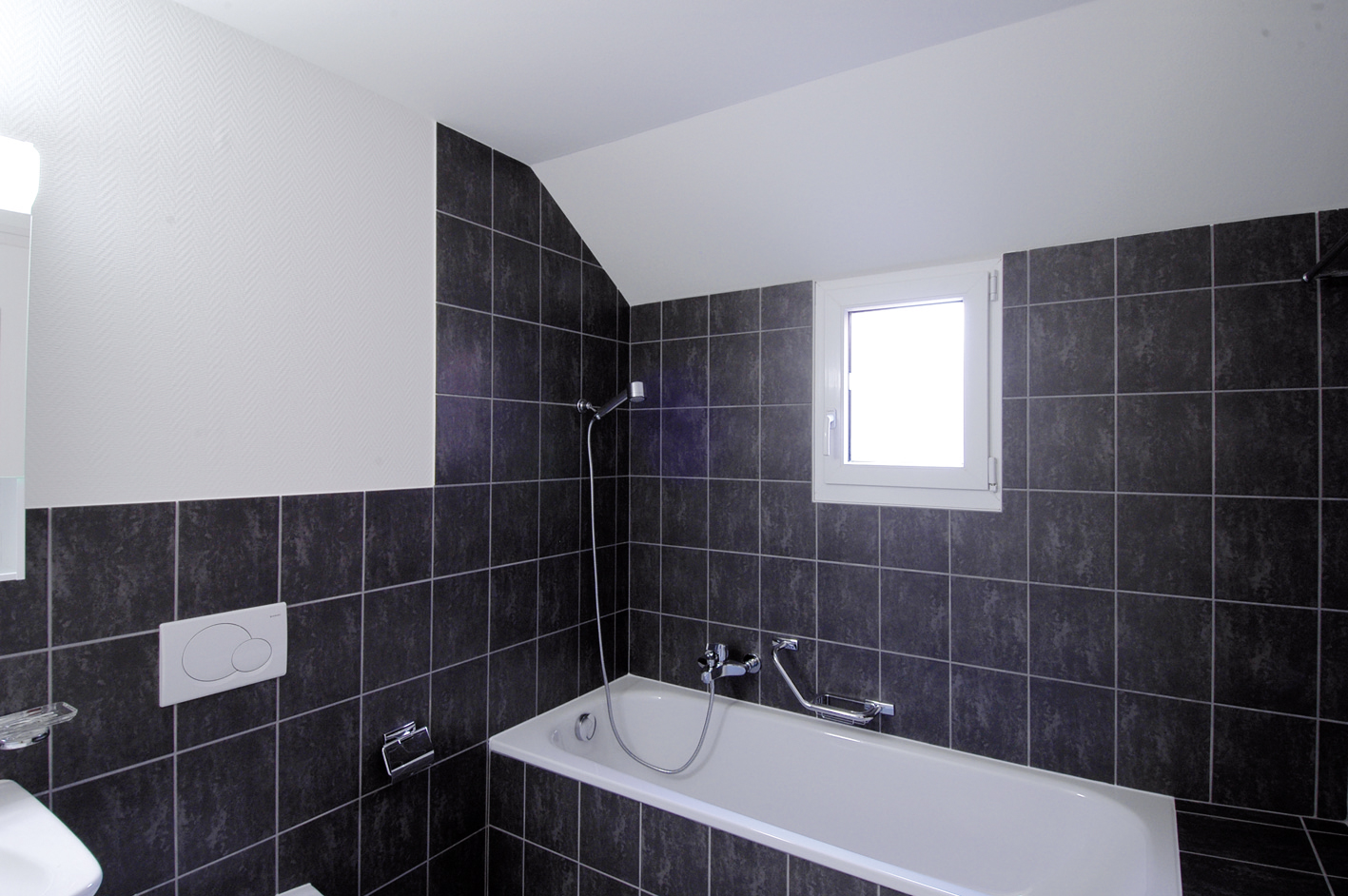 Salle de bains carrelée de noir avec baignoire, immeuble Marc-Dufour