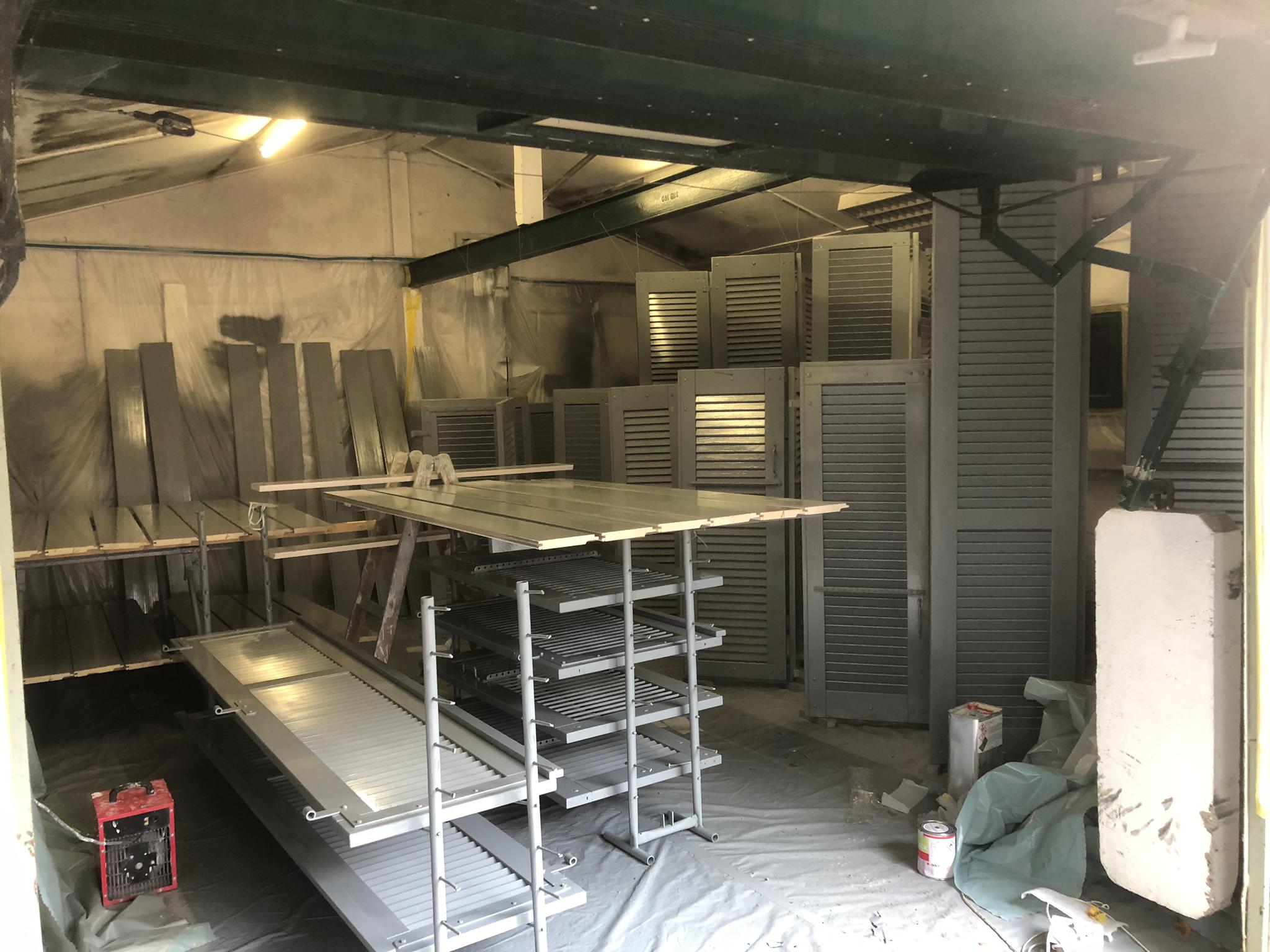 Volets de la maison de maître mis en peinture sous bâche dans l'atelier