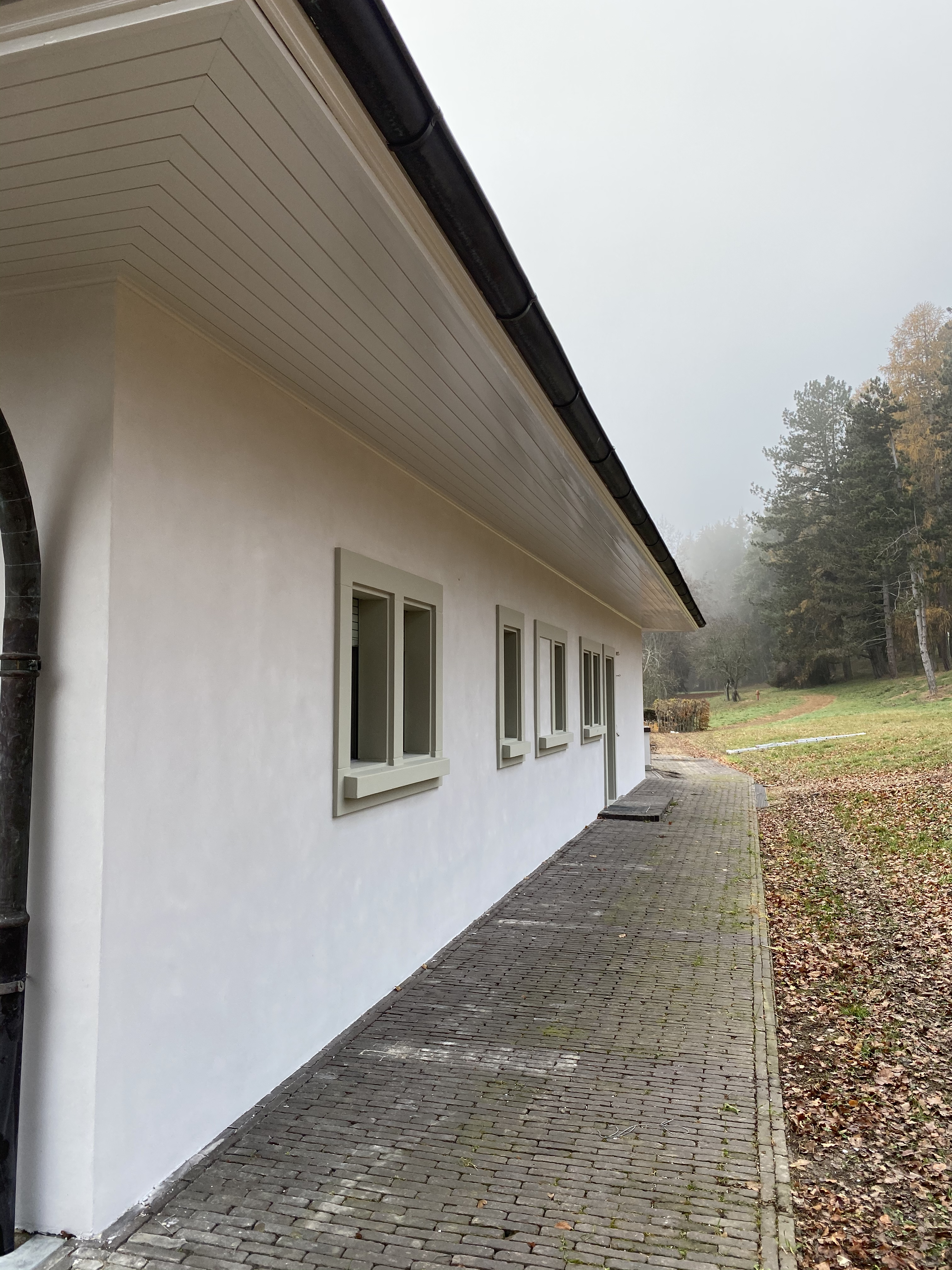 Longue façade blanche de la maison de maître bordée d'une allée pavée