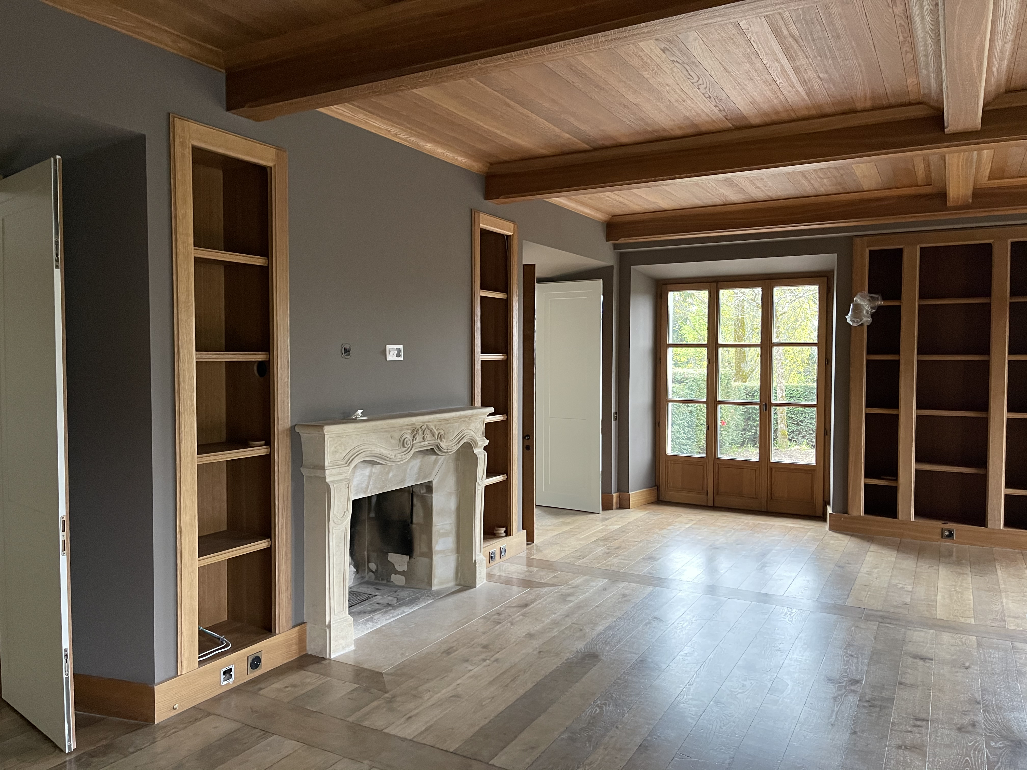Salon de la maison de maître avec cheminée en pierre et bibliothèques encastrées