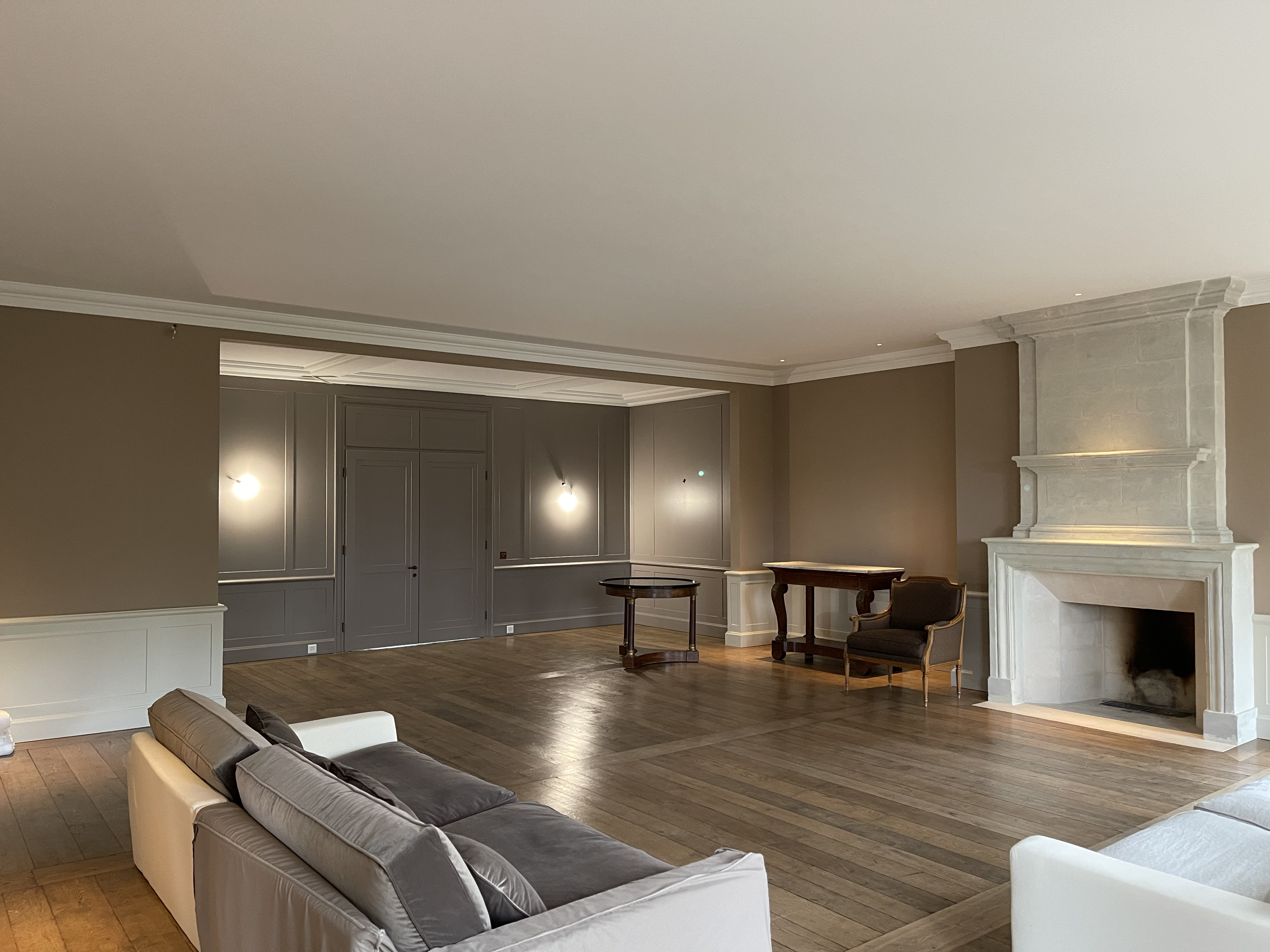 Salon de la maison de maître avec sa cheminée en pierre et son parquet, après rénovation