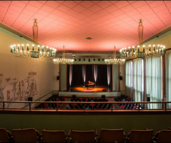 Salle de spectacle de Renens vue du balcon, plafond saumon et lustres en cristal au-dessus des fauteuils