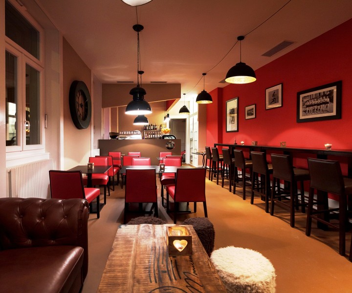 Salle du café Sheep's Coffee à Lausanne, murs rouges, banquette en cuir et cadres au mur