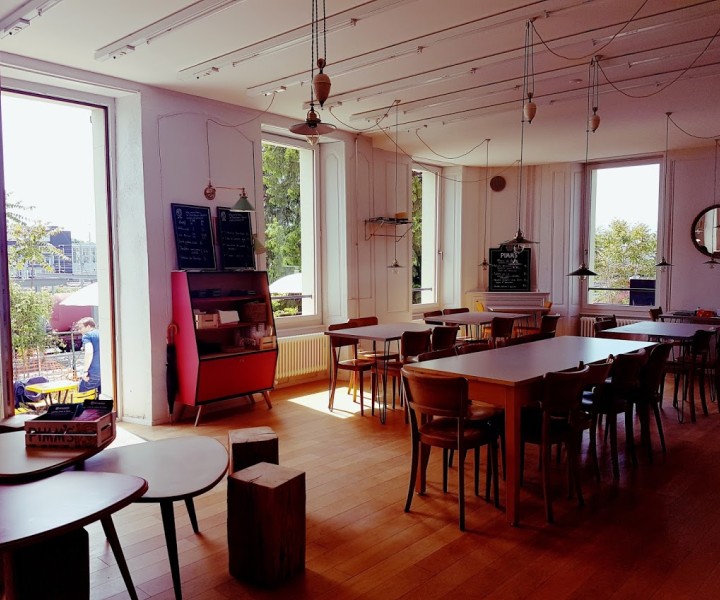 Salle du café de la Ferme des Tilleuls, murs roses et longues tables en bois